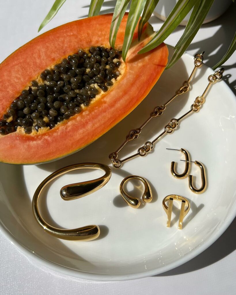 a papaya on a plate next to jewelry from Soko