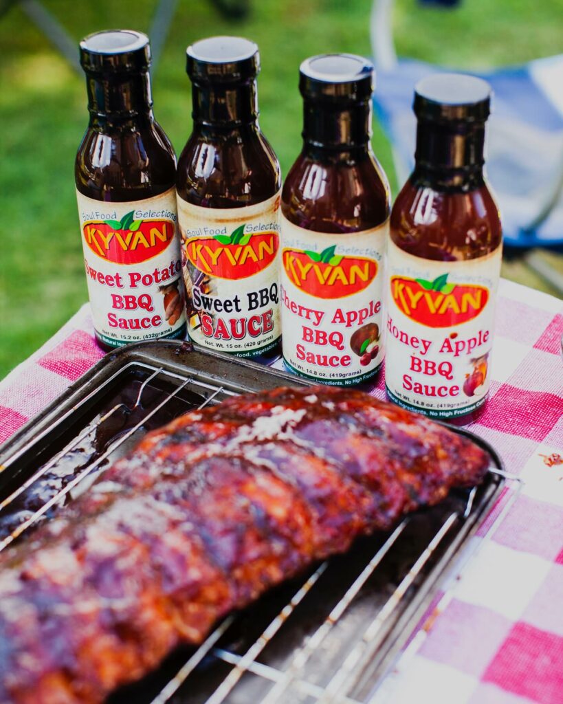 The entire line of Kyvan Foods barbecue sauces on a table with spare ribs