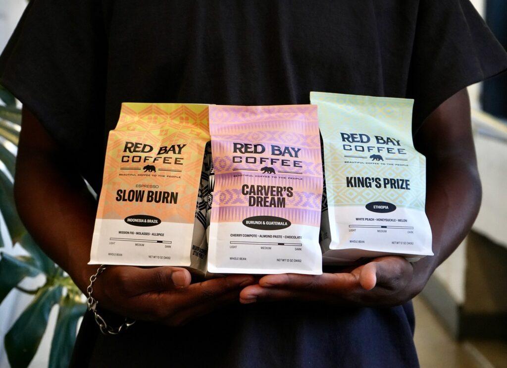 A Man holds three bags of Red Bay Coffee