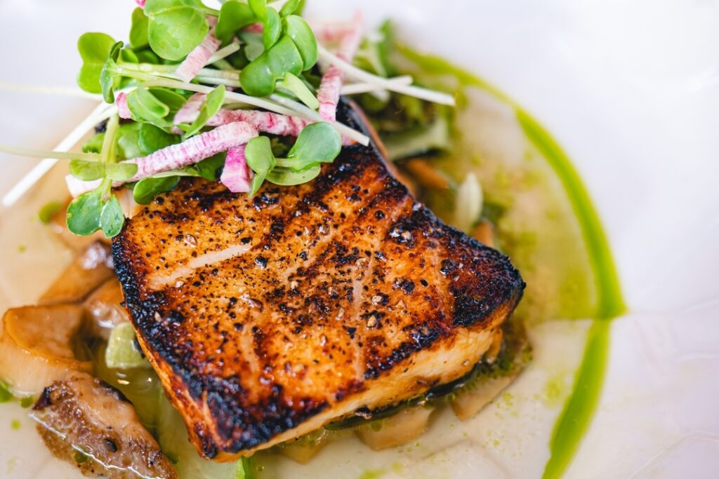 Savor the rich flavors of our Misoyaki Black Cod with shishito, tatsoi, and warm ginger dashi from international Smoke